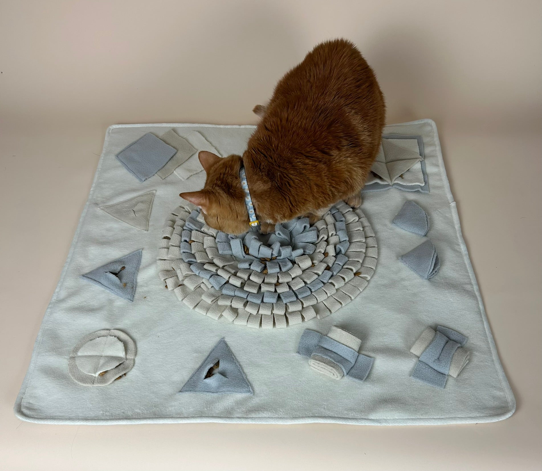 Cat using The Nest Mat calm enrichment mat for slow feeding and foraging